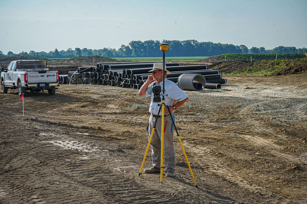 man standing behind surveyor on construction site