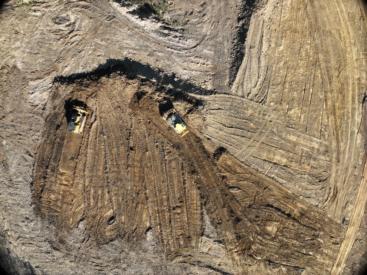Aerial view of heavy machinery driving through dirt on a construction site