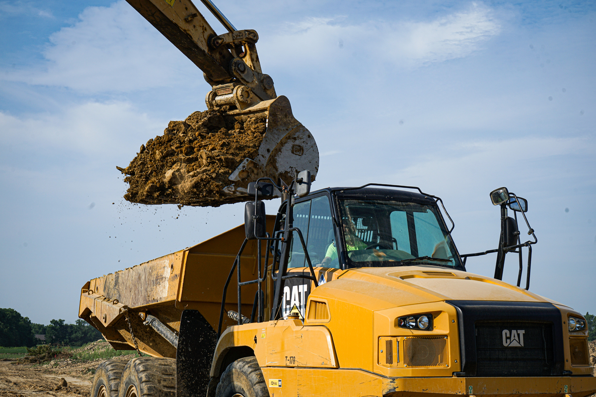 excavator scooping dirt into a dump truck