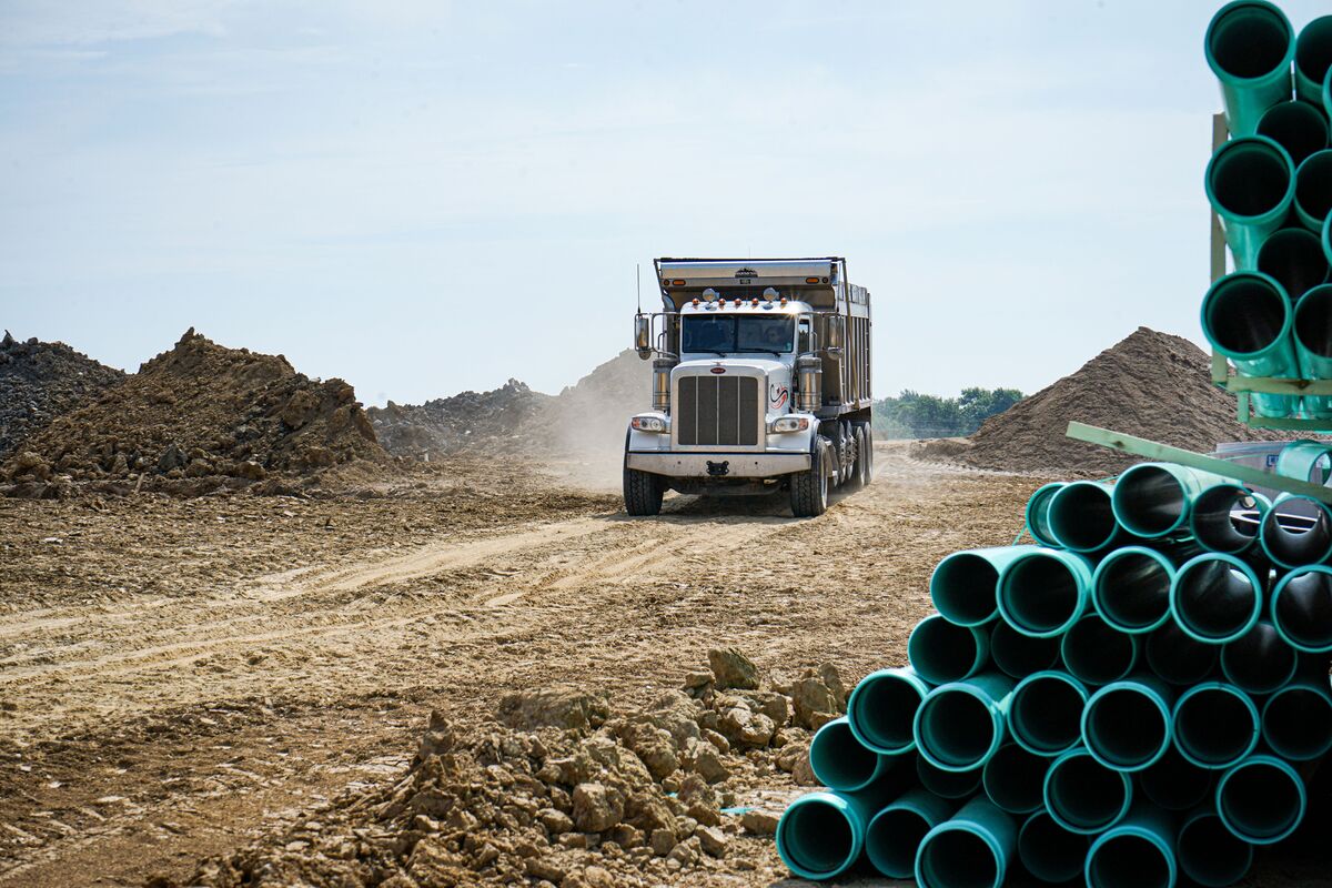 truck driving through dirt, next to large pipes