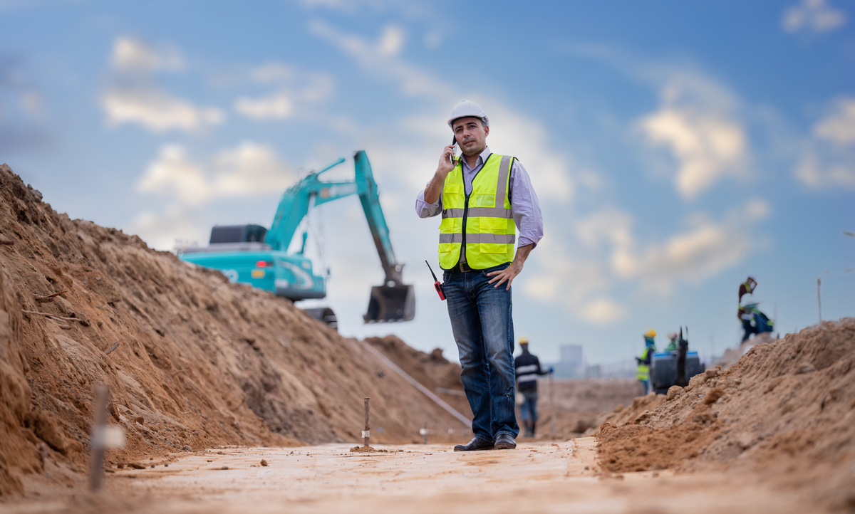 construction engineer wearing safety gear on a construction site talking on a phone