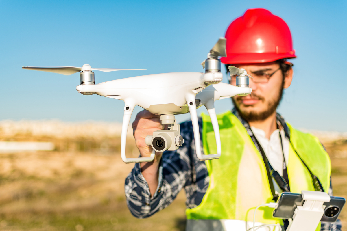 construction worker holding a white drone