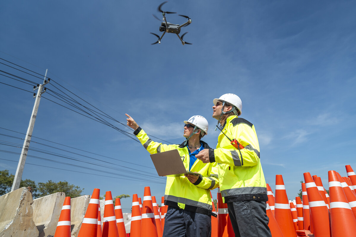 two construction workers operating a drone in a construction zone 